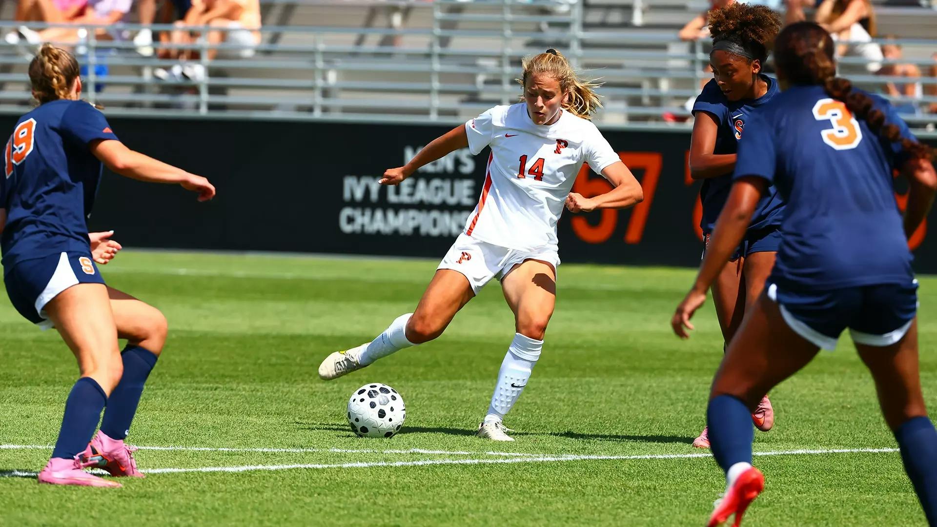 Girl in white and orange jersey dribbles 