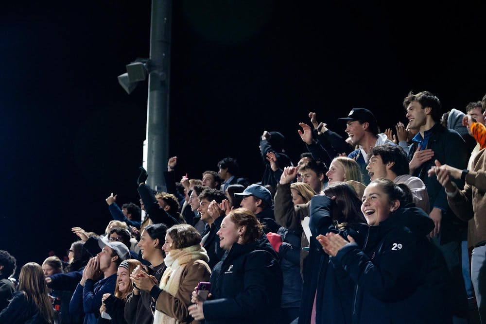 A group of students cheering from the stands during a soccer game.