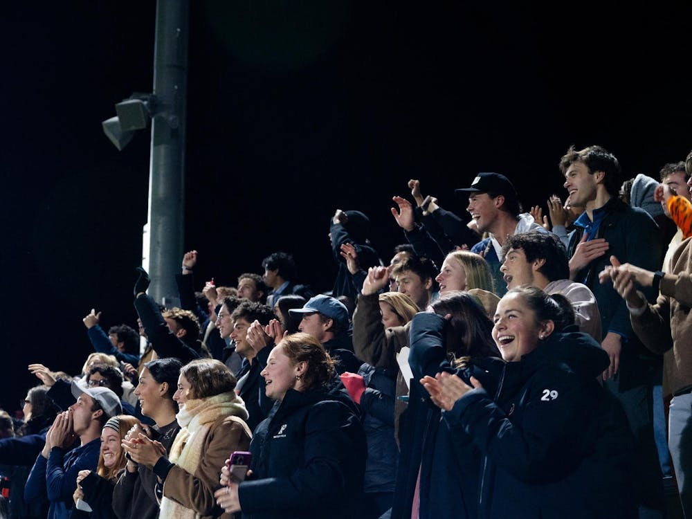 A group of students cheering from the stands during a soccer game.