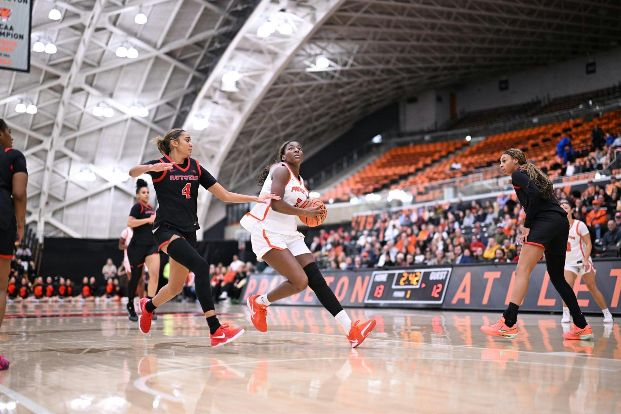 A&#x20;woman&#x20;in&#x20;a&#x20;white&#x20;and&#x20;orange&#x20;jersey&#x20;shoots&#x20;a&#x20;layup&#x20;while&#x20;another&#x20;player&#x20;in&#x20;a&#x20;black&#x20;jersey&#x20;tries&#x20;to&#x20;stop&#x20;her.