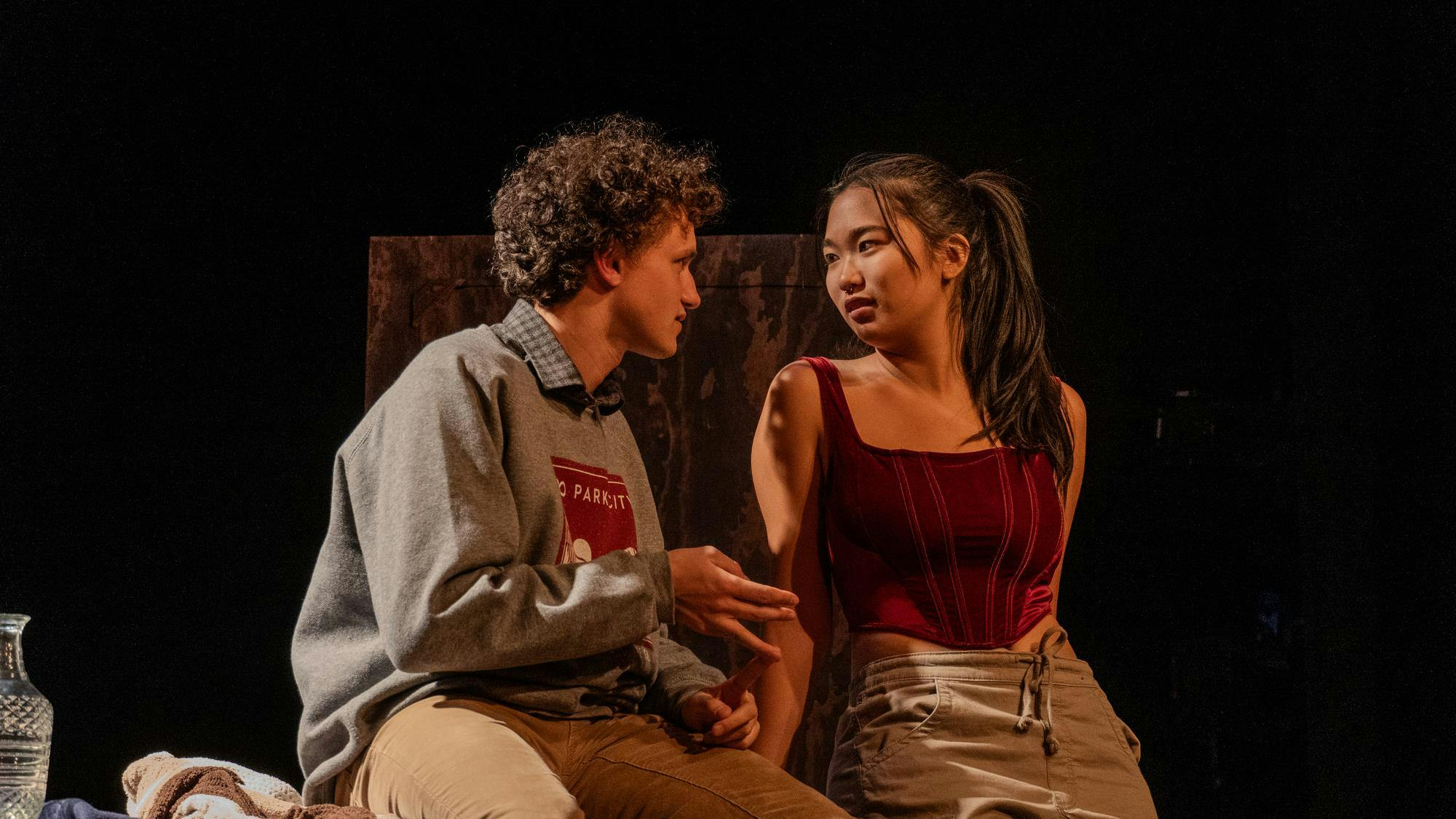 A man and a woman look at each other while talking on-stage.