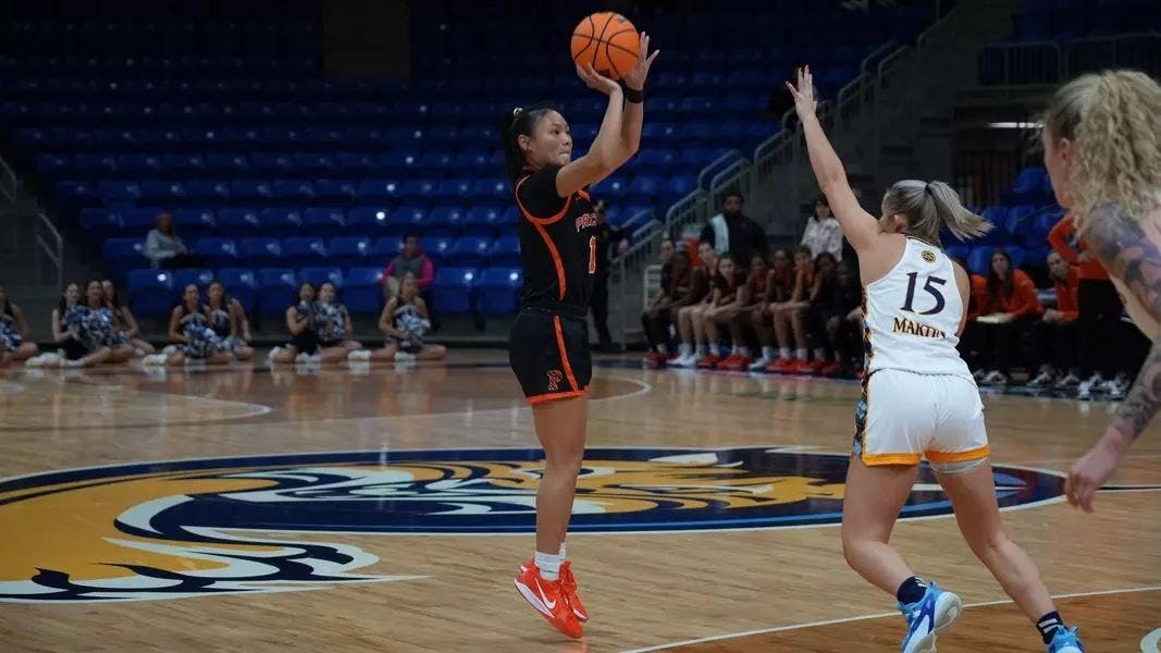 Player in Princeton uniform shooting a three pointer over the hands of a Quinnipiac player 