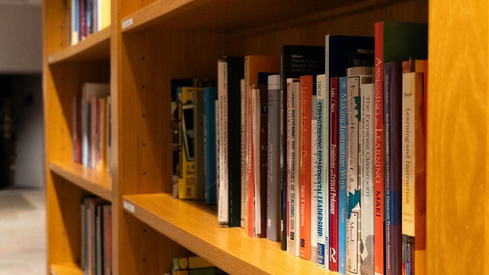 Mostly orange and blue books sit on a shelf.