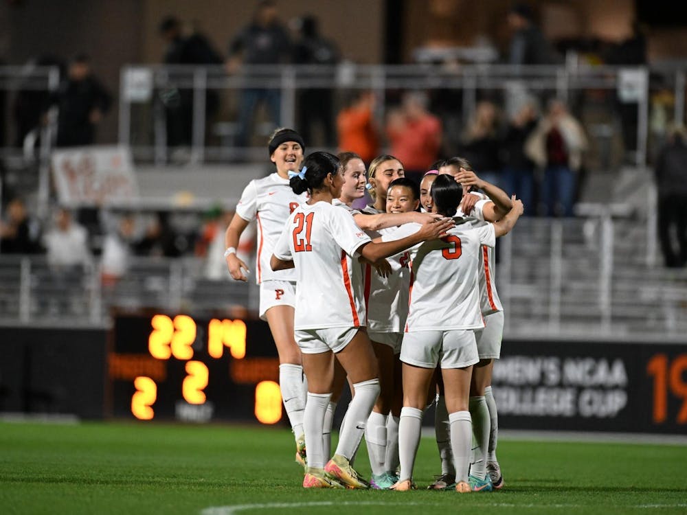 A group of woman wearing white jerseys and shorts embrace together after scoring a goal.