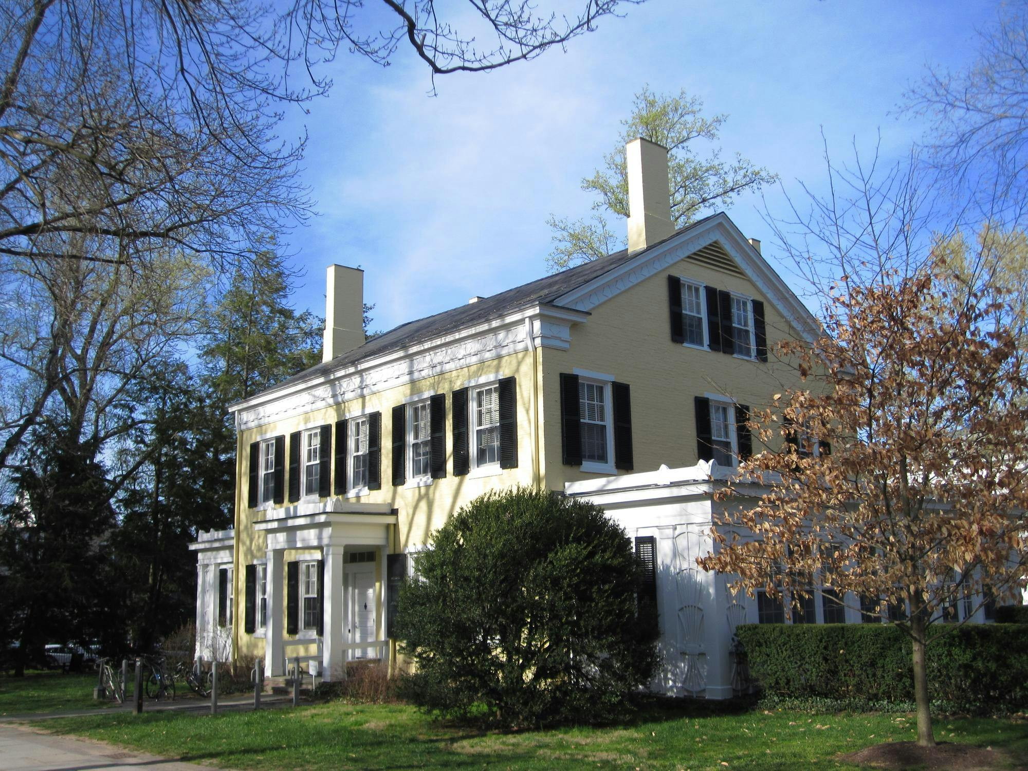 Yellow brick house with white trim and white columns in front. 