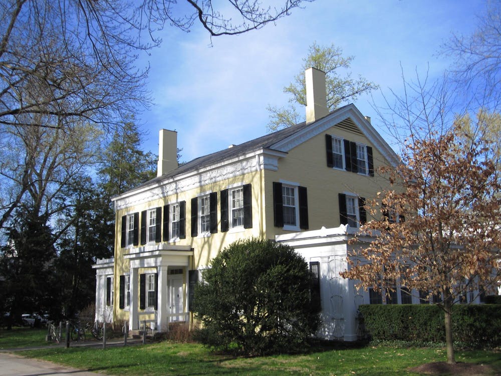 Yellow brick house with white trim and white columns in front. 