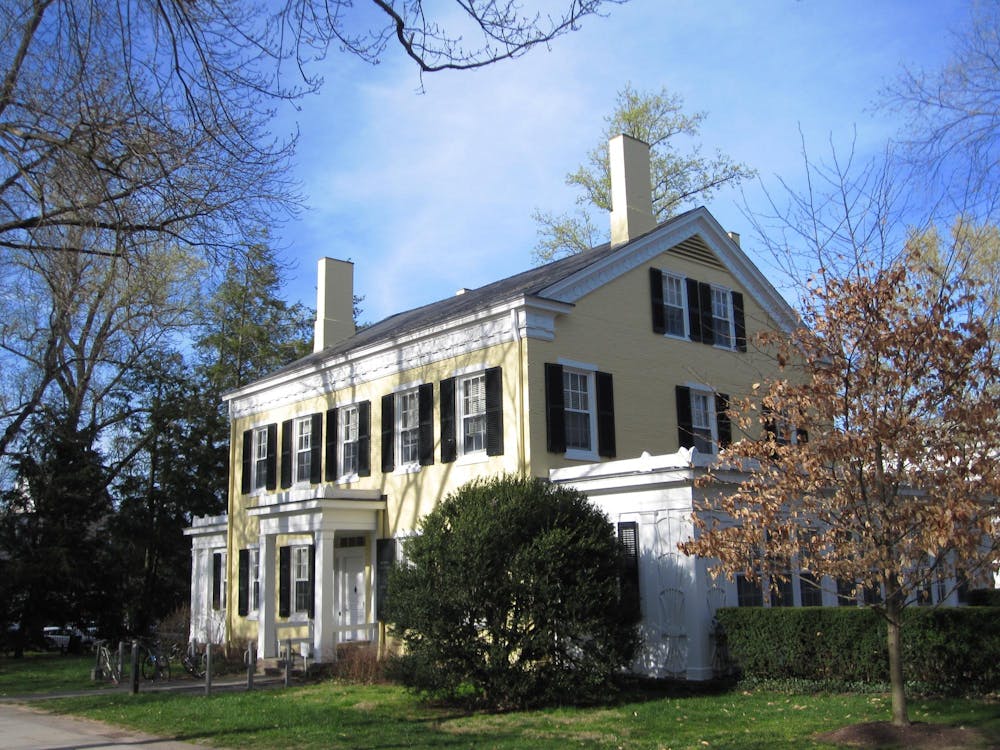 Yellow brick house with white trim and white columns in front.