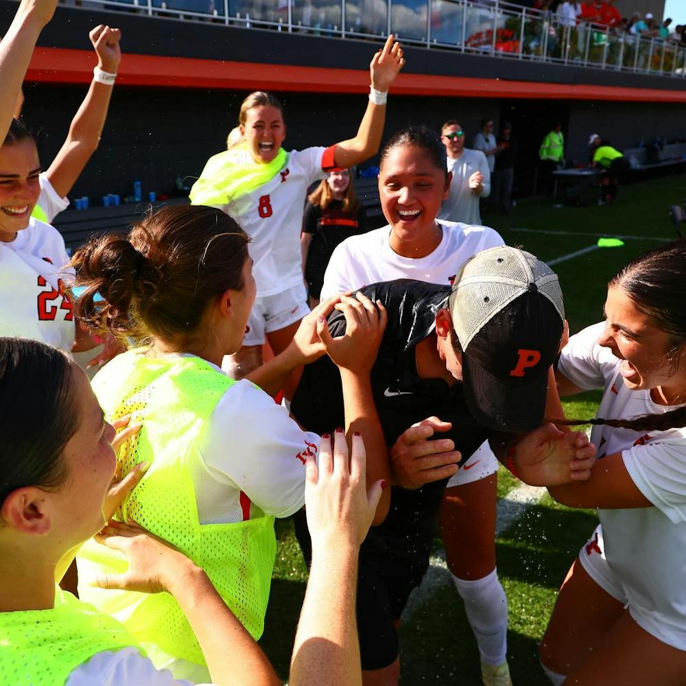 Women wearing white, orange, and black uniforms. Hands are up in the air.