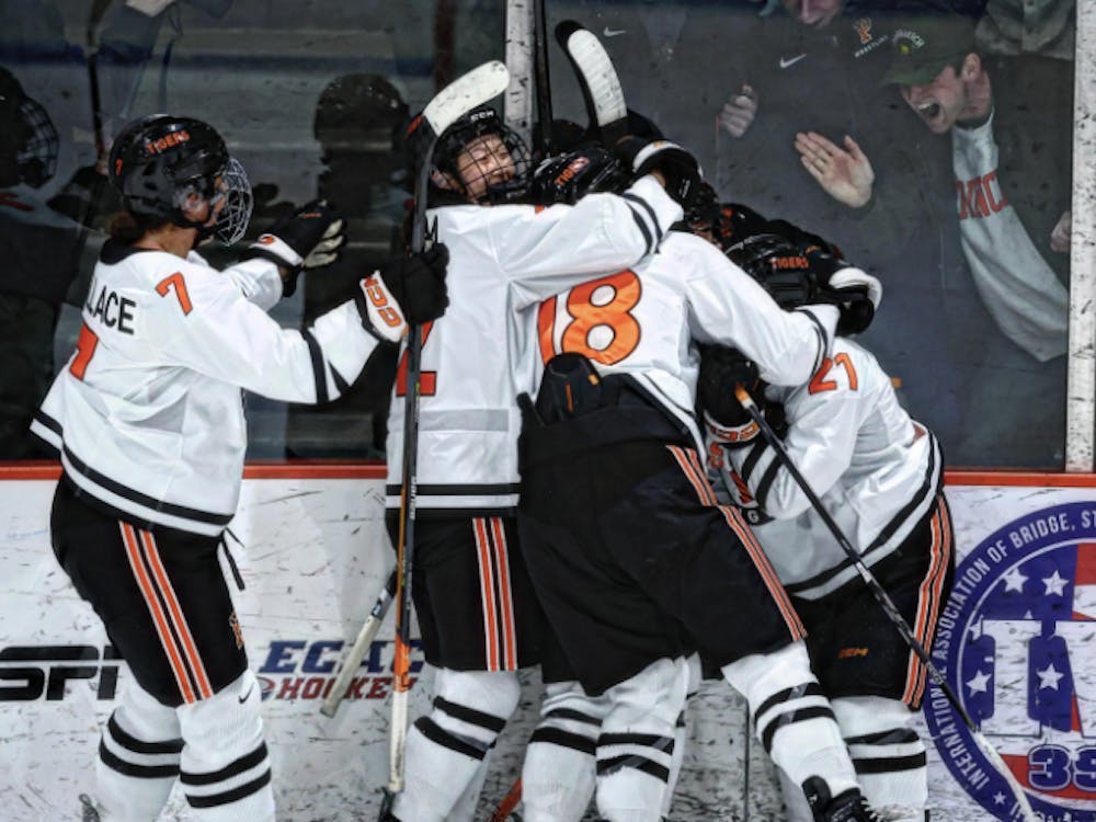 Players in white and orange uniforms hug another player with fans cheering through the glass.