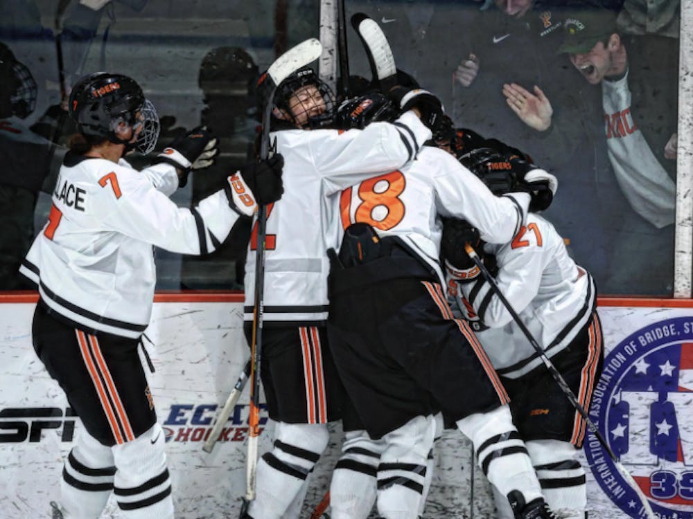 Players in white and orange uniforms hug another player with fans cheering through the glass. 