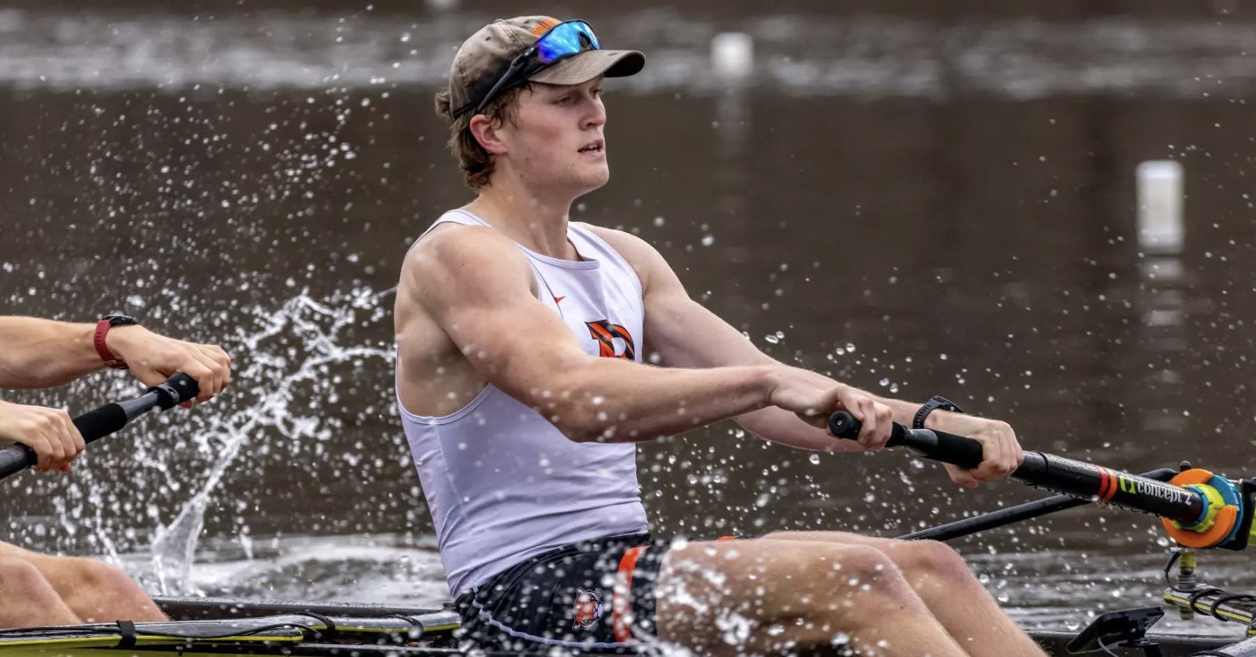 A man in a white jersey rowing in the water.