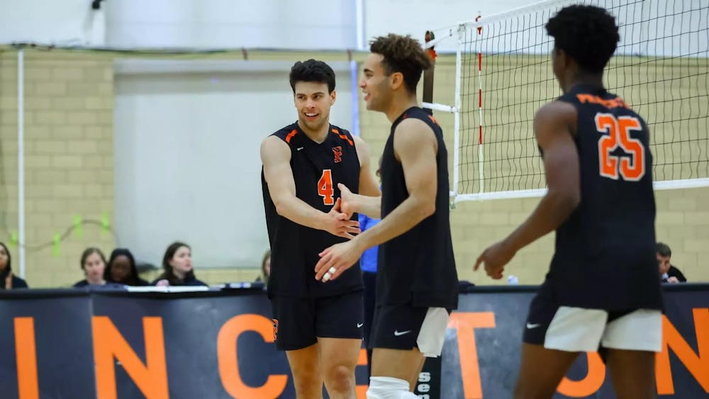 Volleyball players in black uniforms high five on the court.