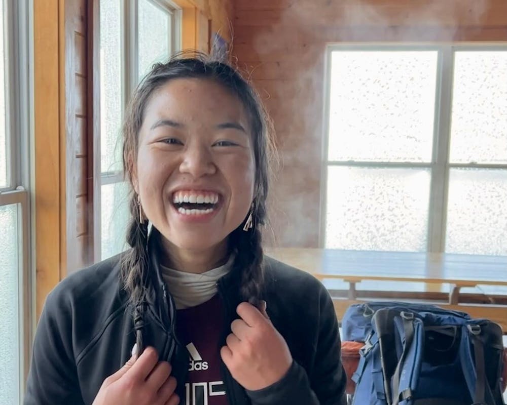 A young woman with her hair in two braids grins at the camera