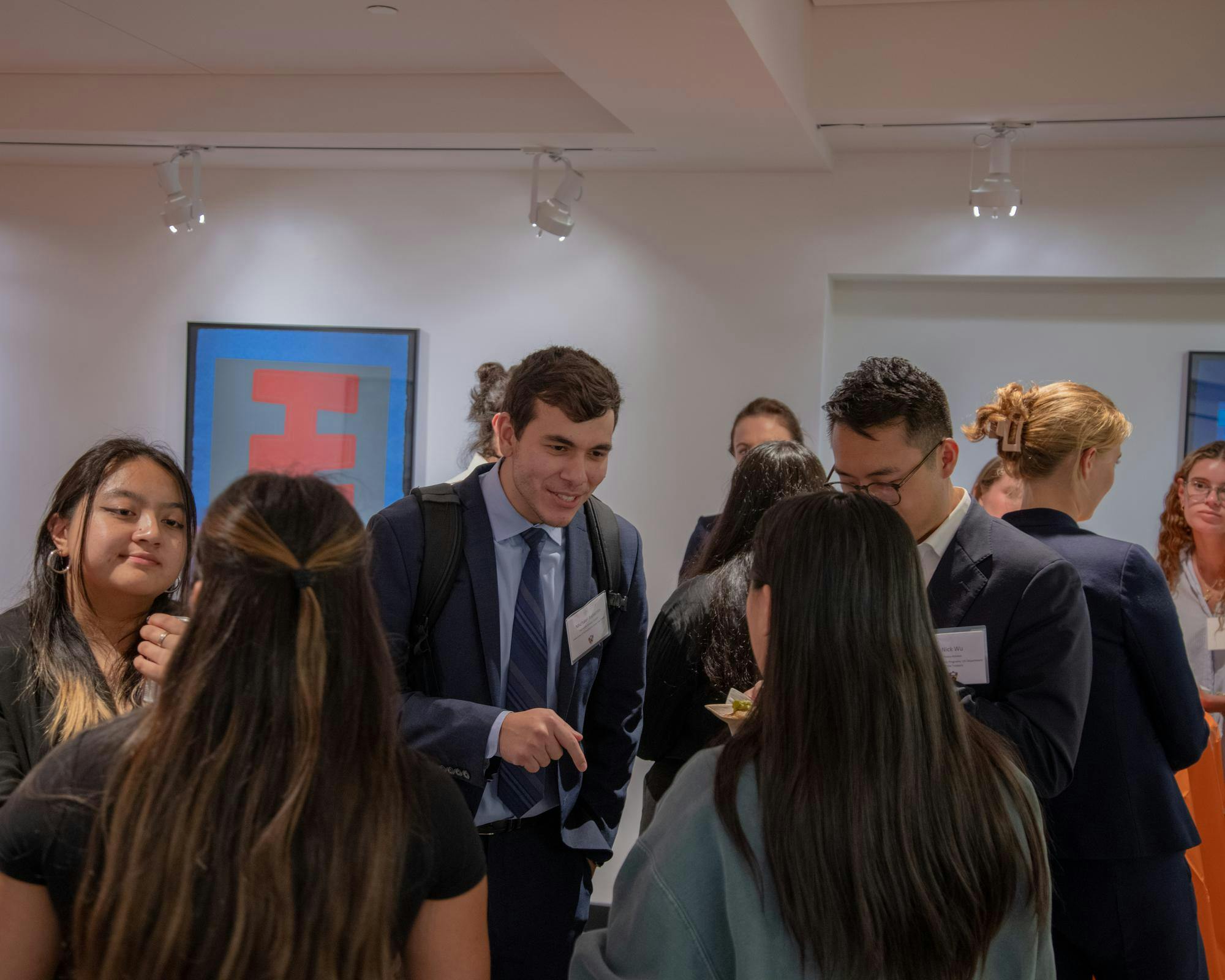 Several people are stood around talking. They are wearing suits and other formalwear.