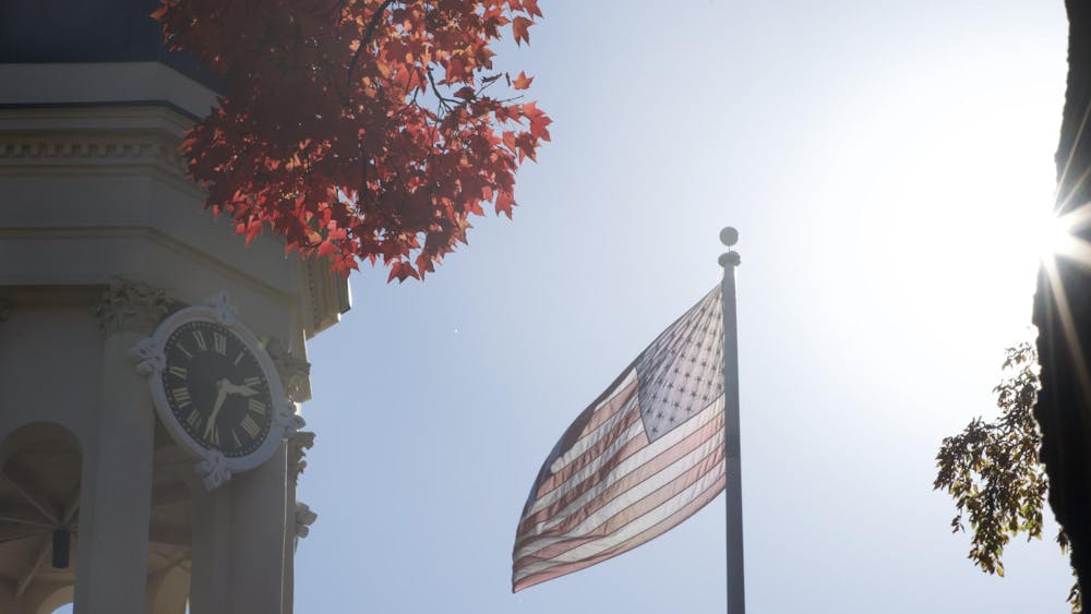 American flag flies on a sunny day next to a tan bell tower.