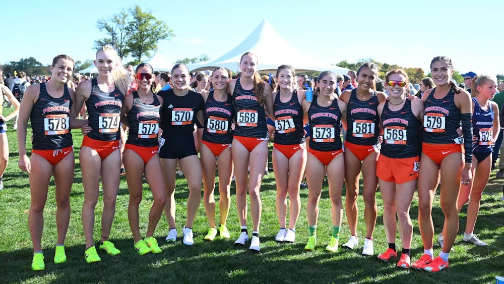Women in black running shirts and orange shorts line up for a photo.