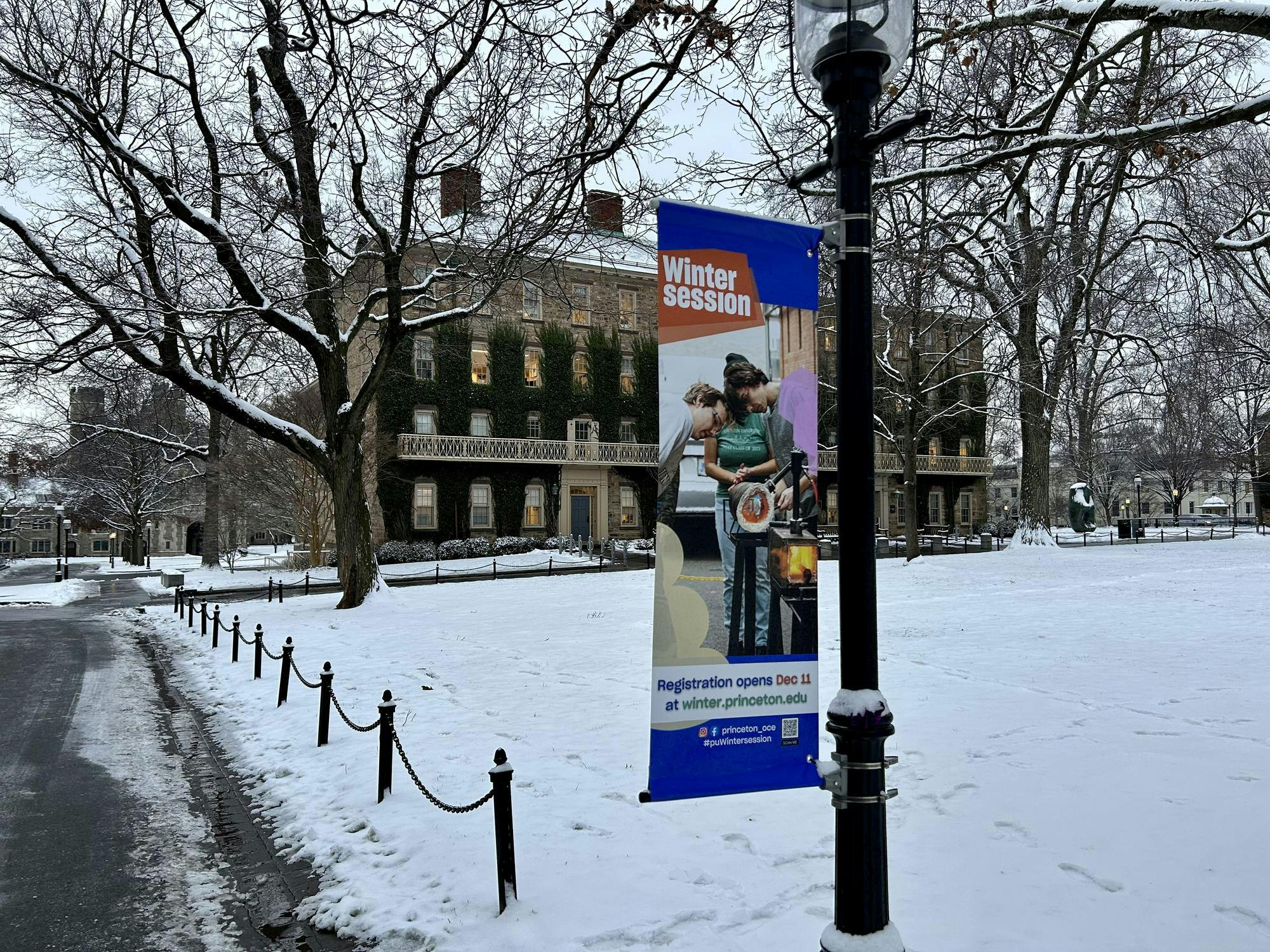 A multicolored banner reading "Wintersession" hangs from a light pole on a snow-covered field.