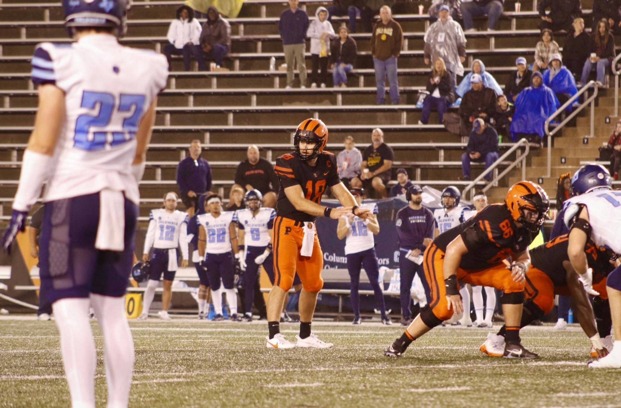 Man in orange and black waits with others for football with arms stretched out. 