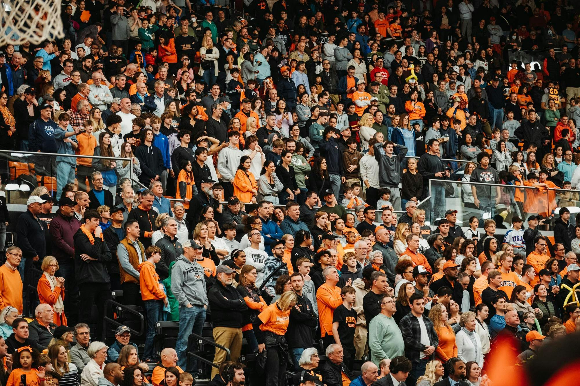 A large gathering of fans wearing mostly black and orange sit in the lower tier of the Jadwin Gymnasium stands.