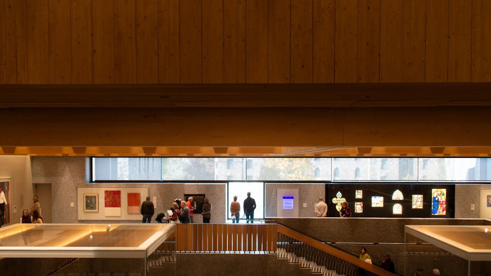 A downward view of people looking at a wall of art, including paintings and stained glass.
