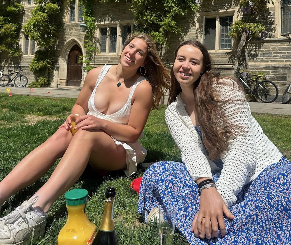 Girl in white dress with girl in white sweater and blue dress, sitting on the grass