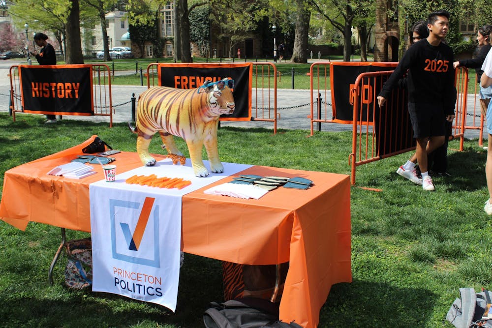 Tiger on a table with orange tablecloth, with a cloth titled “PRINCETON POLITICS” draped on the table.