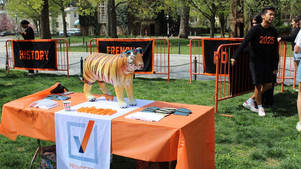 Tiger on a table with orange tablecloth, with a cloth titled “PRINCETON POLITICS” draped on the table.