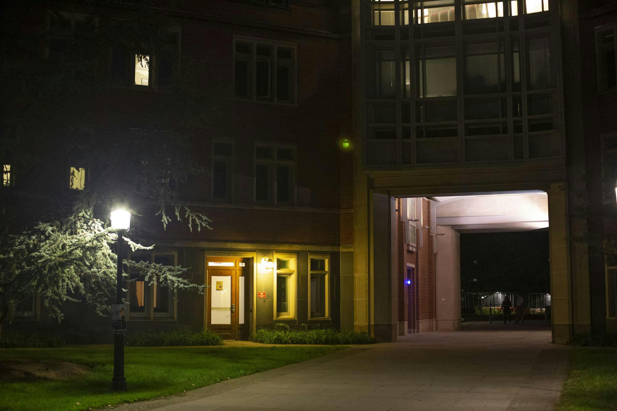 The arch under Bloomberg Hall is dimly lit in the dark with a streetlight on the left.