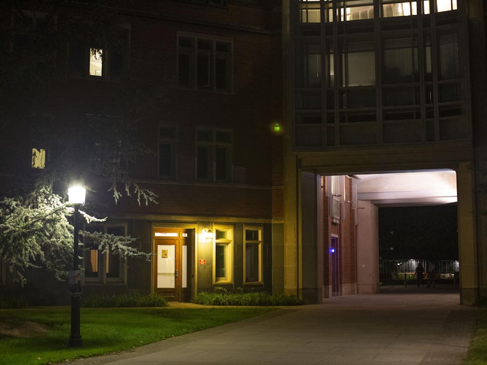 The arch under Bloomberg Hall is dimly lit in the dark with a streetlight on the left.