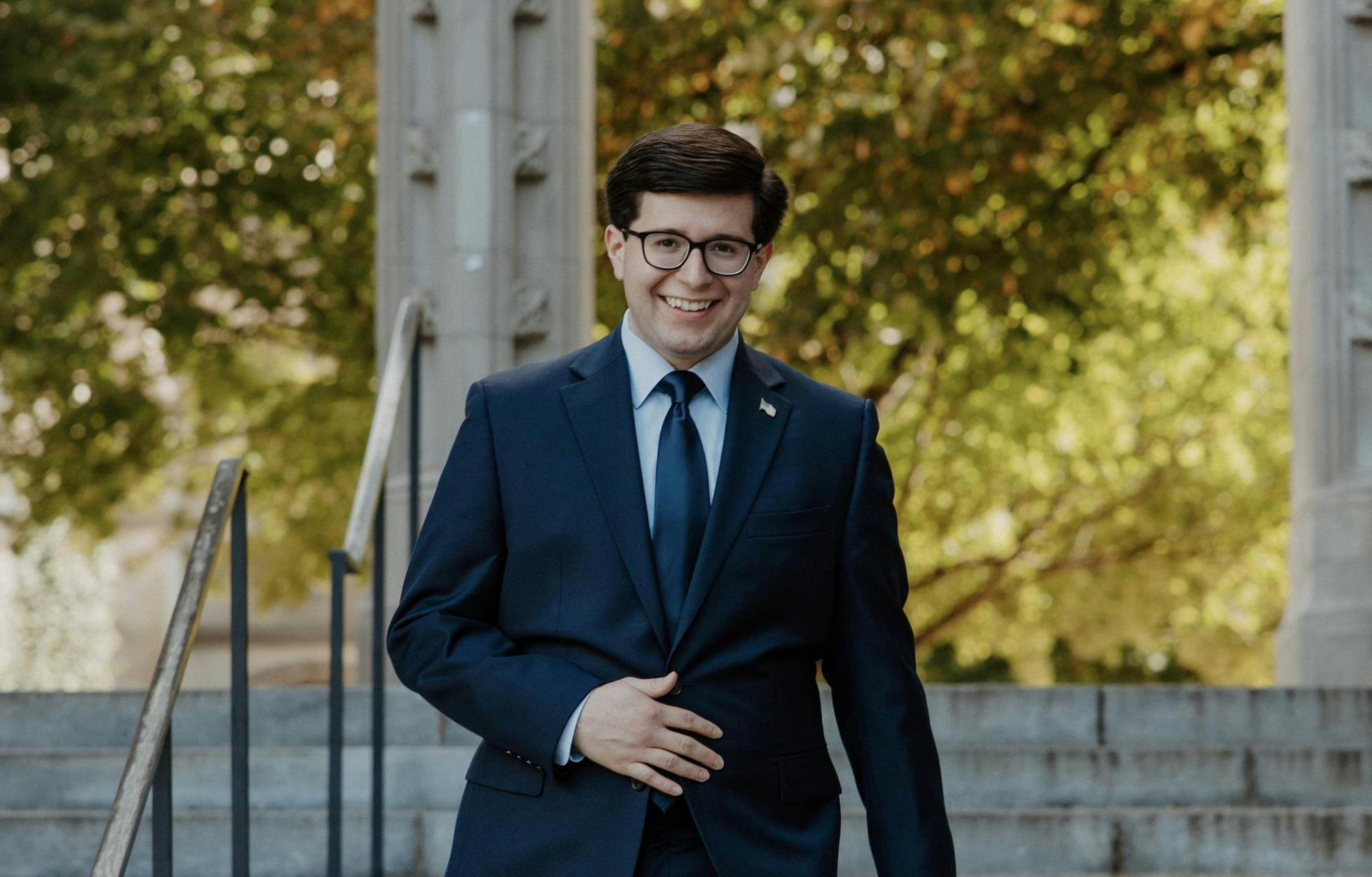 A man in a blue suit walks down stairs. 