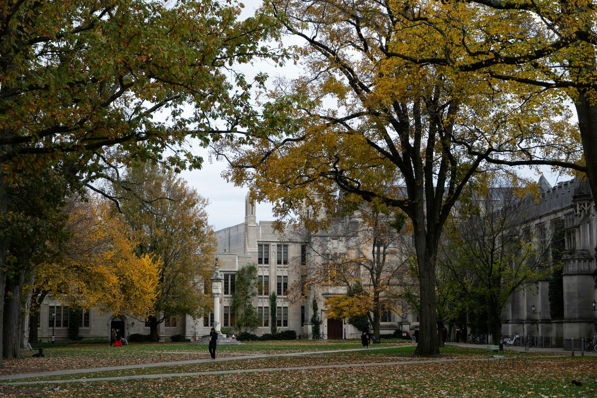 Gothic courtyard with criss crossing pathways and leaves changing color from green to yellow.