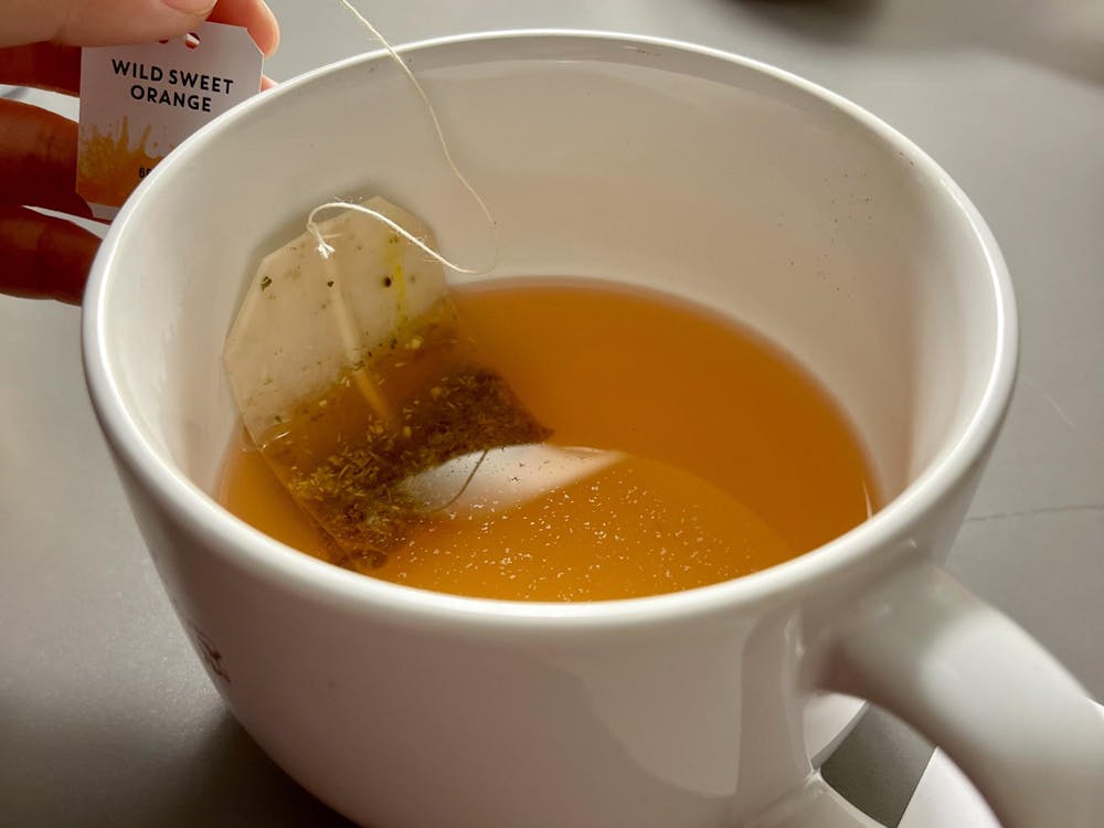 A white mug filled with orange liquid and a teabag.