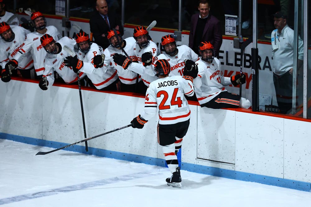 Ice hockey player skating past bench of players.