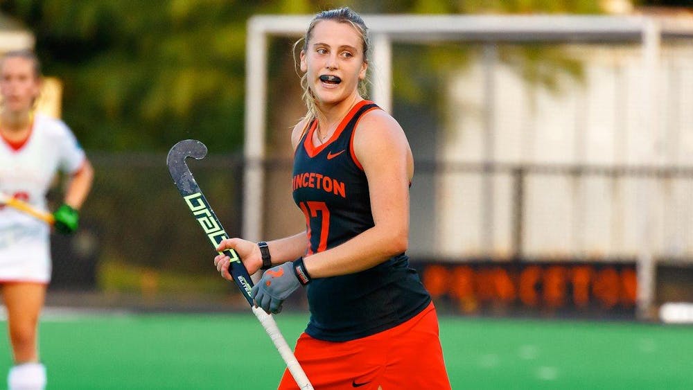 princeton field hockey player in orange and black holds stick 