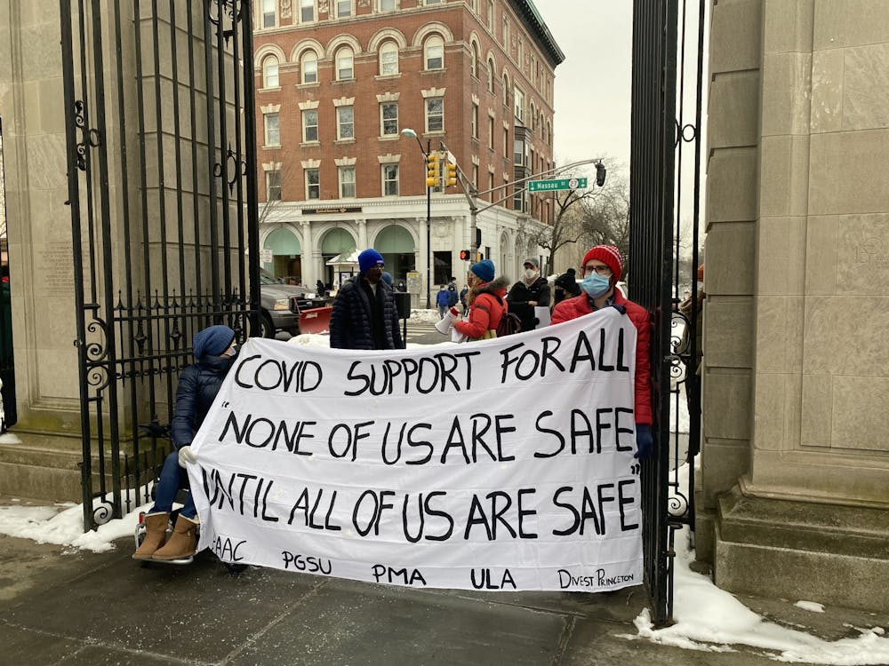 <h5>Protestors hold sign reading “COVID SUPPORT FOR ALL” at FitzRandolph Gate.</h5>
<h6>Marissa Michaels / The Daily Princetonian</h6>