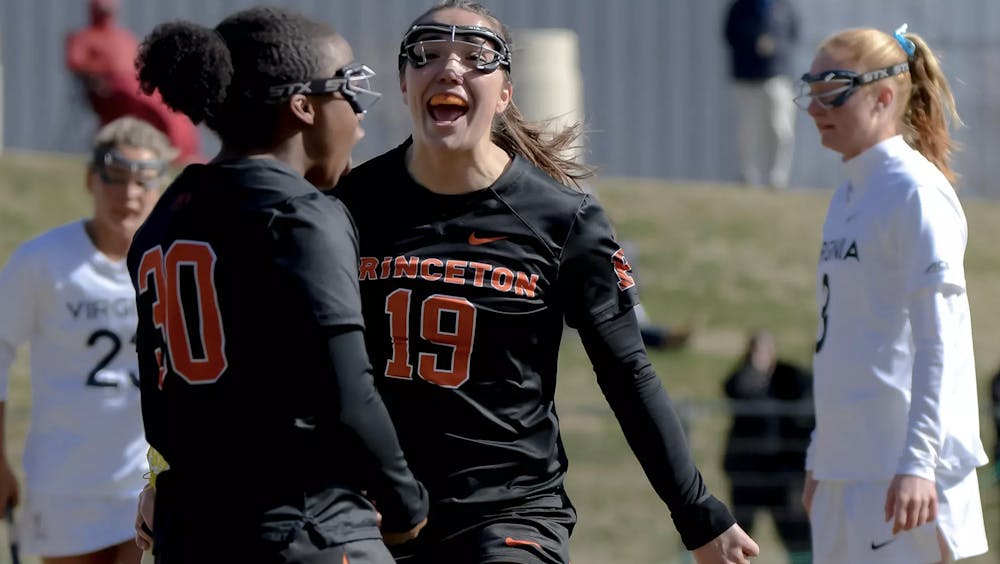 Women in black and orange yelling in celebration after a goal. 