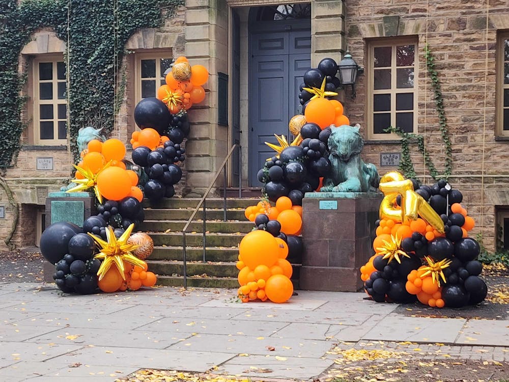 A photo of orange and black balloons outside a stone building with two Tiger statues. 
