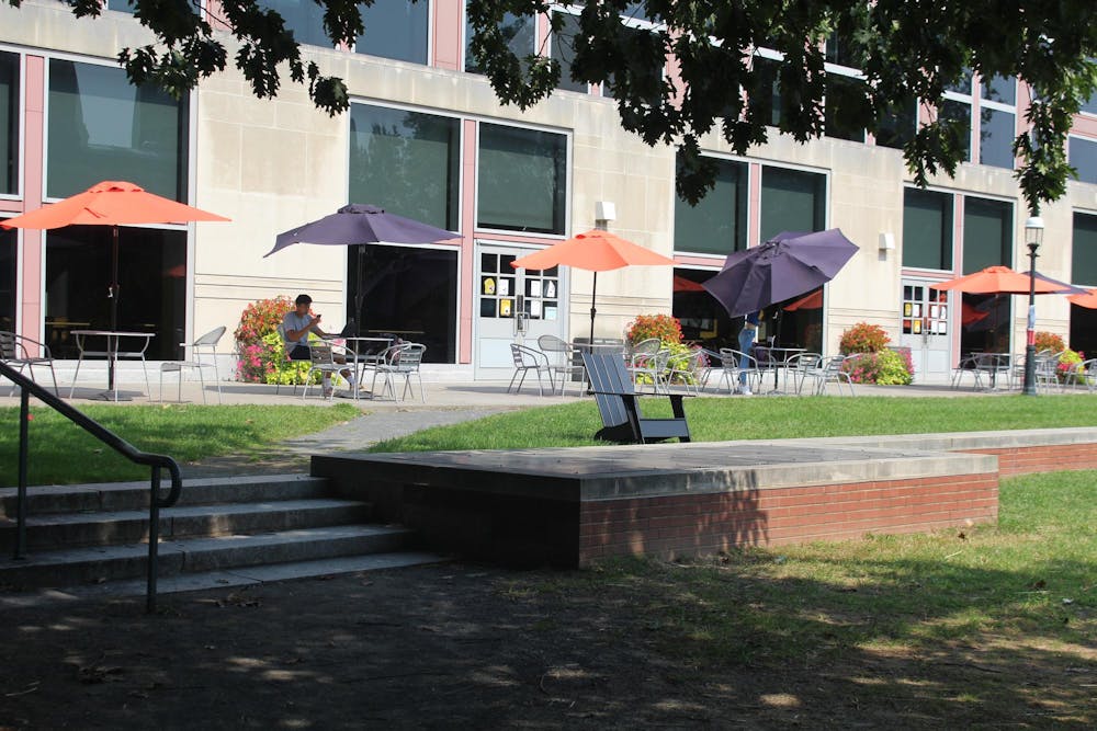 Patio with orange and purple umbrellas over metal tables and chairs.