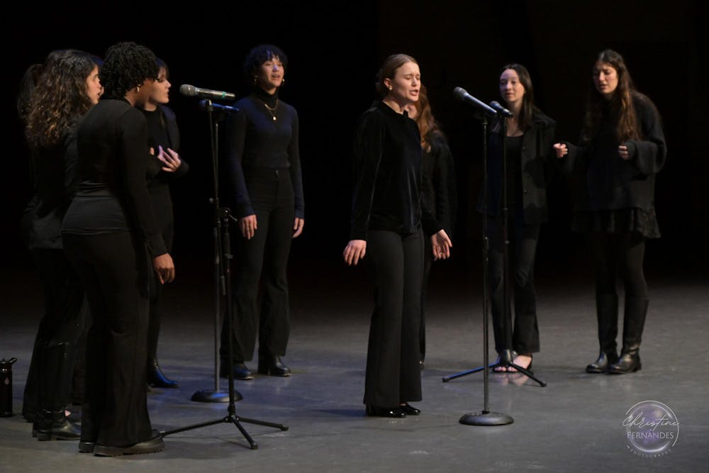 Eight performers dressed in all black, singing into two microphones.