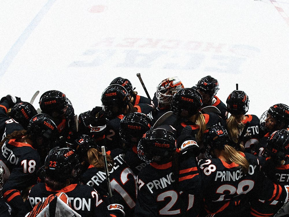 Princeton women's ice hockey players in black jerseys together in big group on bench.