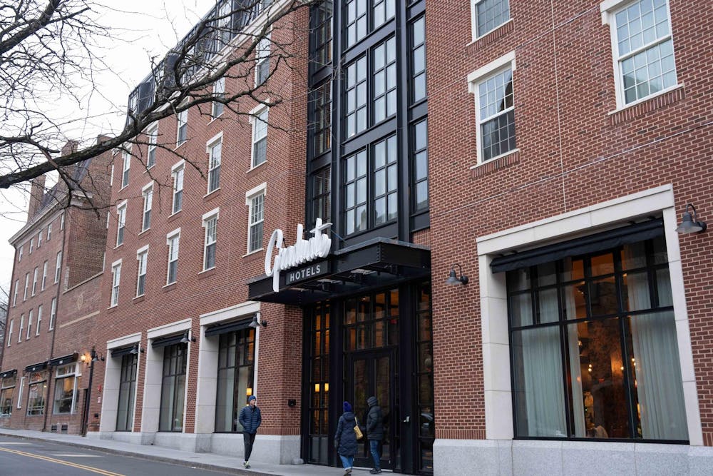 A red-brick building with the black-metal front entrance canopy displaying a sign titled “Graduate Hotels.”