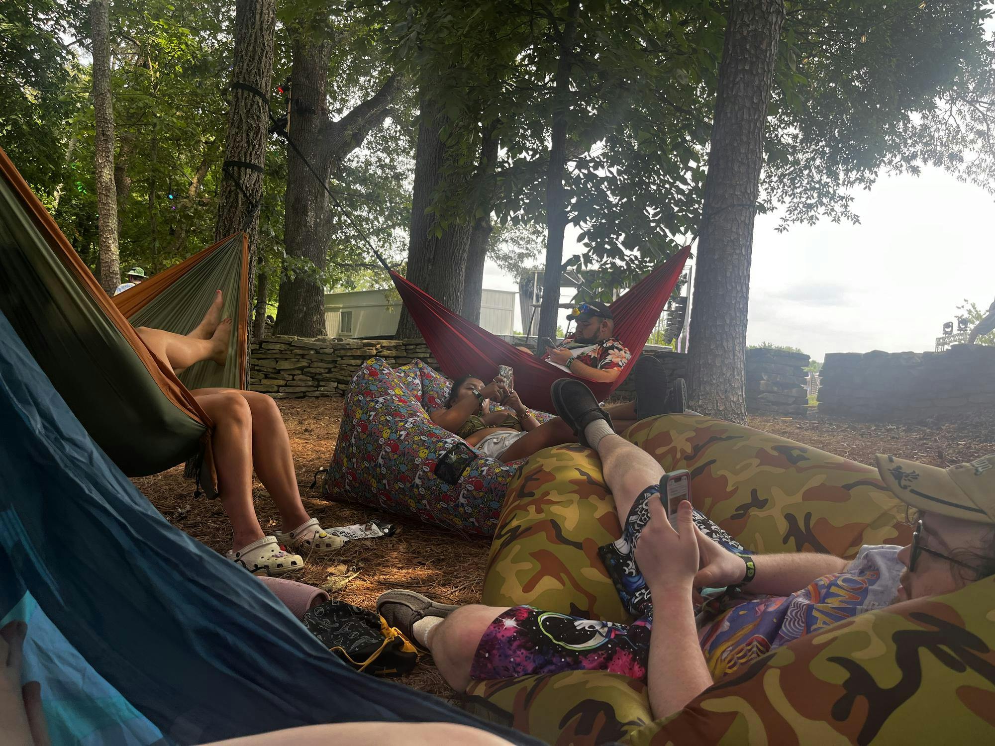 Six young people in bright colored clothing are laying down or sitting in a variety of hammocks and multi-colored inflatable chairs.