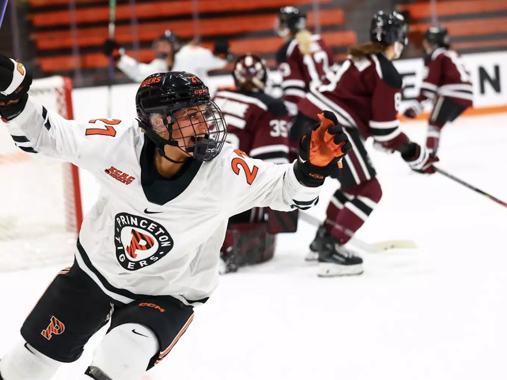 A woman in a white, orange, and black jersey celebrating after scoring a goal.