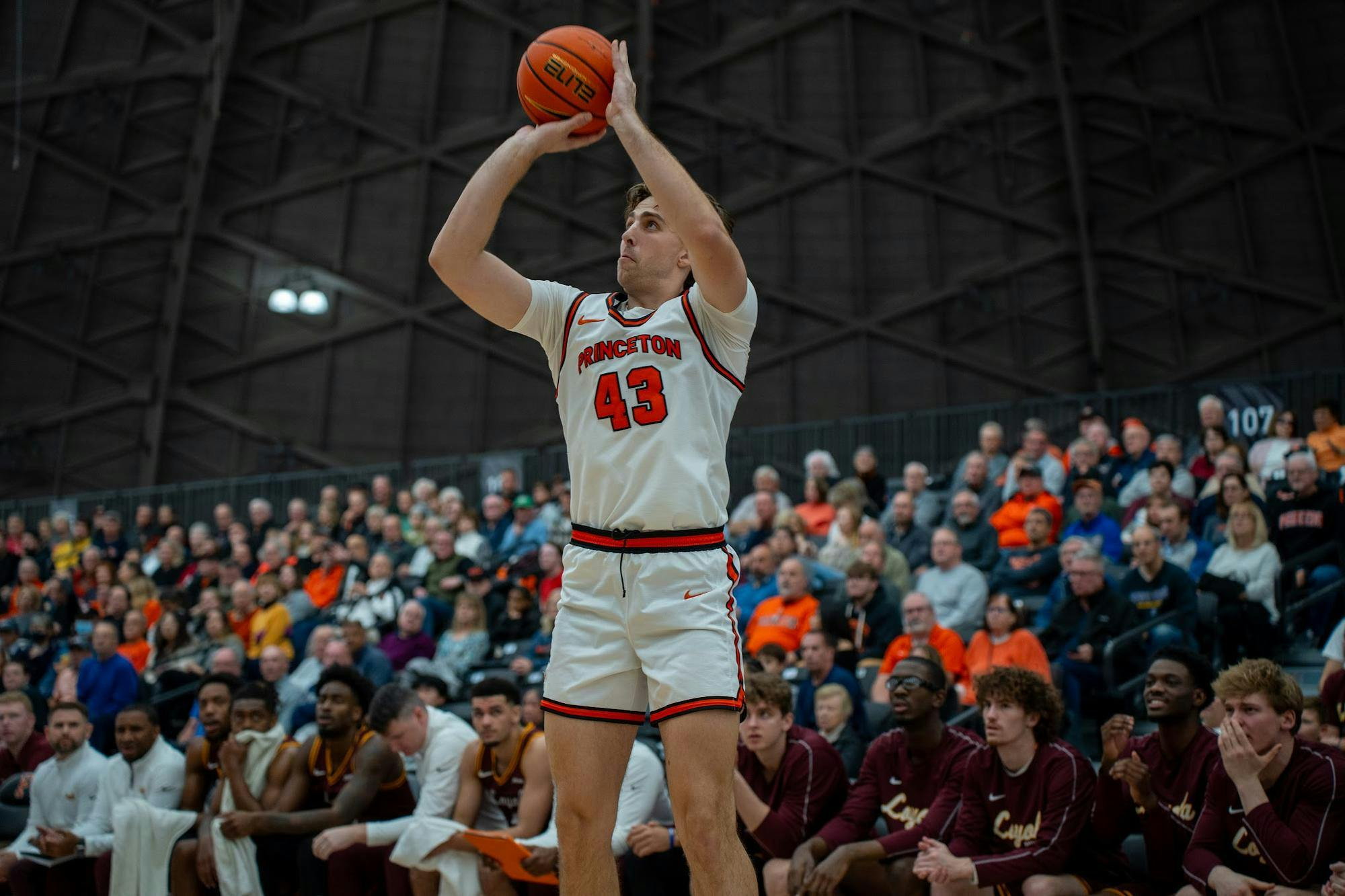 A man wearing a white jersey shooting a basketball on the court. 