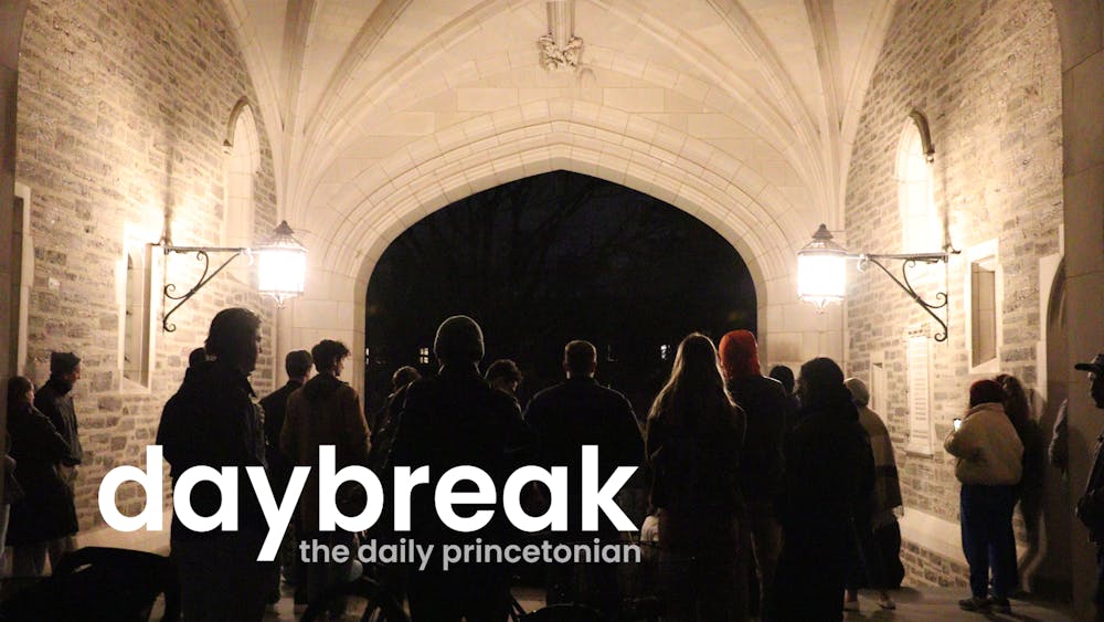 A dimly lit archway with two bright lights on each side. In the middle there are people in a circle, singing. In the foreground, a logo says "Daybreak: the daily princetonian"