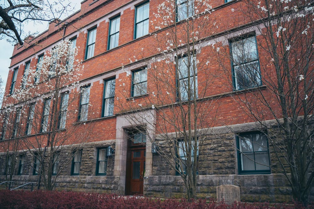 The photo shows a red building with several barren trees in the foreground.