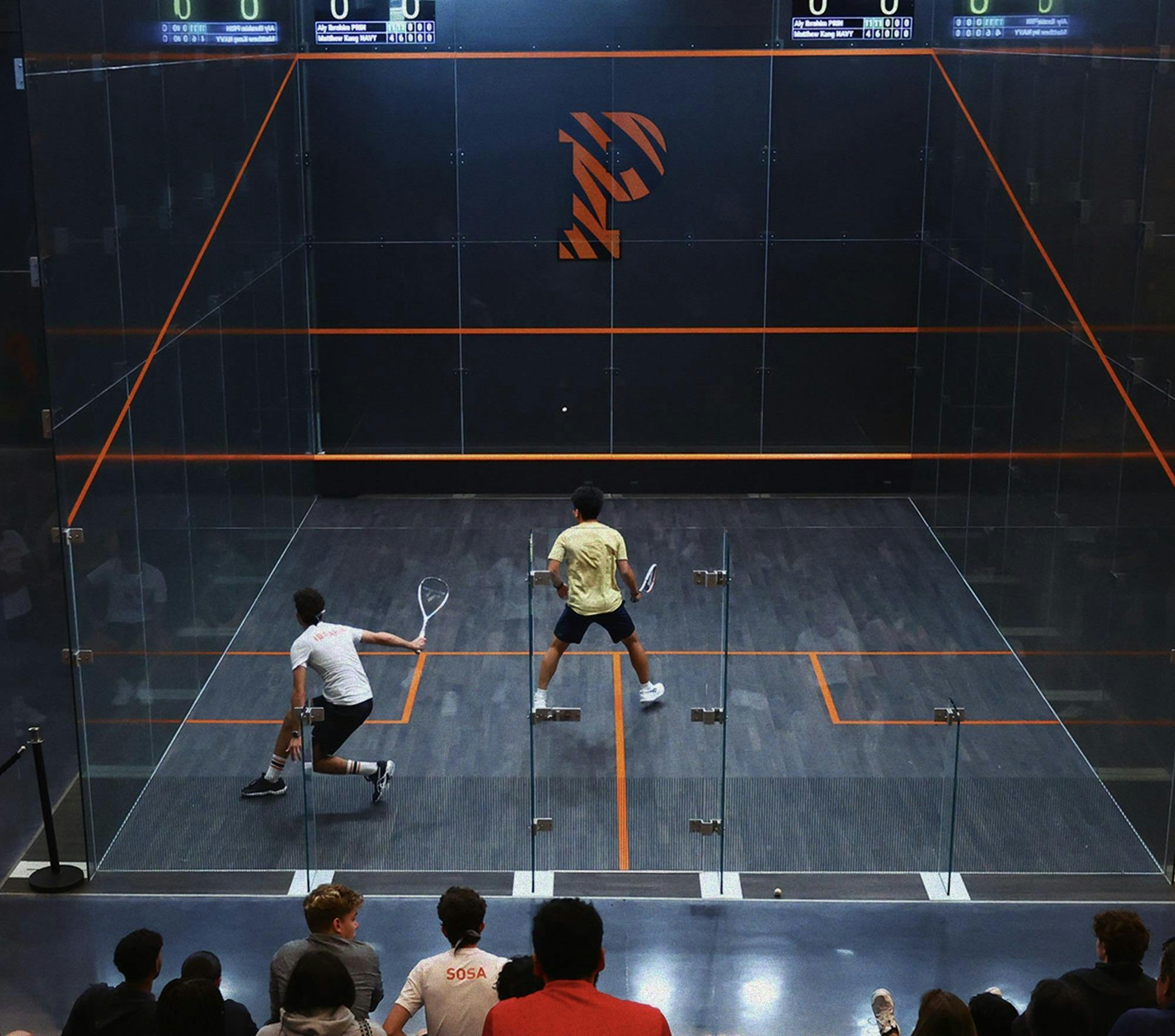 Man in white shirt plays man in gold shirt in squash