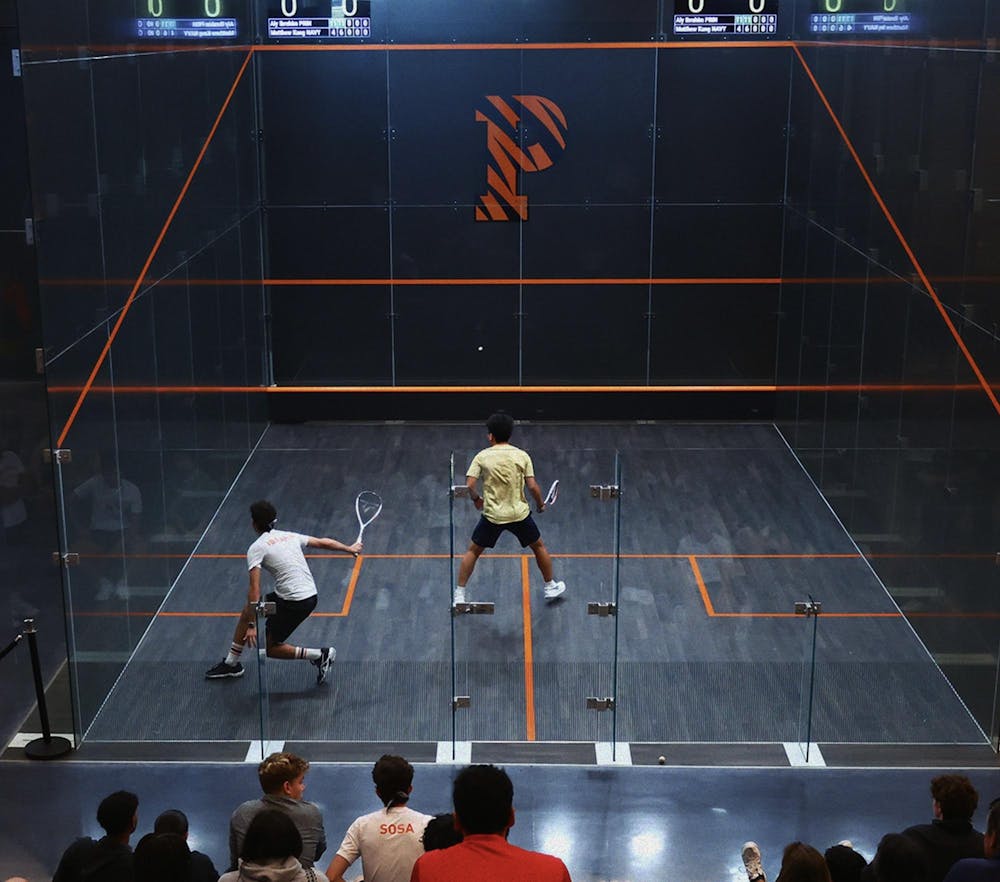 Man in white shirt plays man in gold shirt in squash