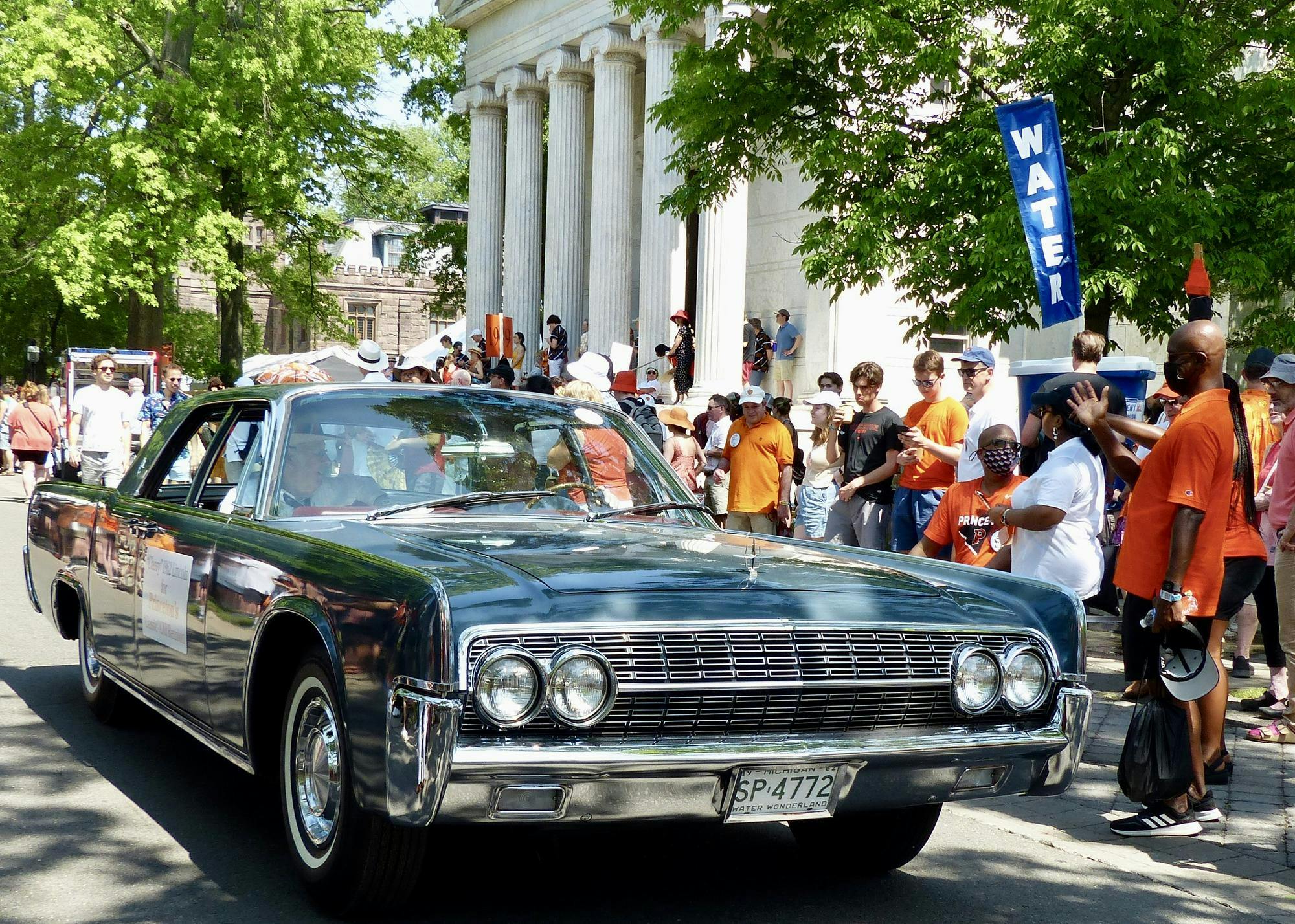Green car in front of crowd of onlookers.