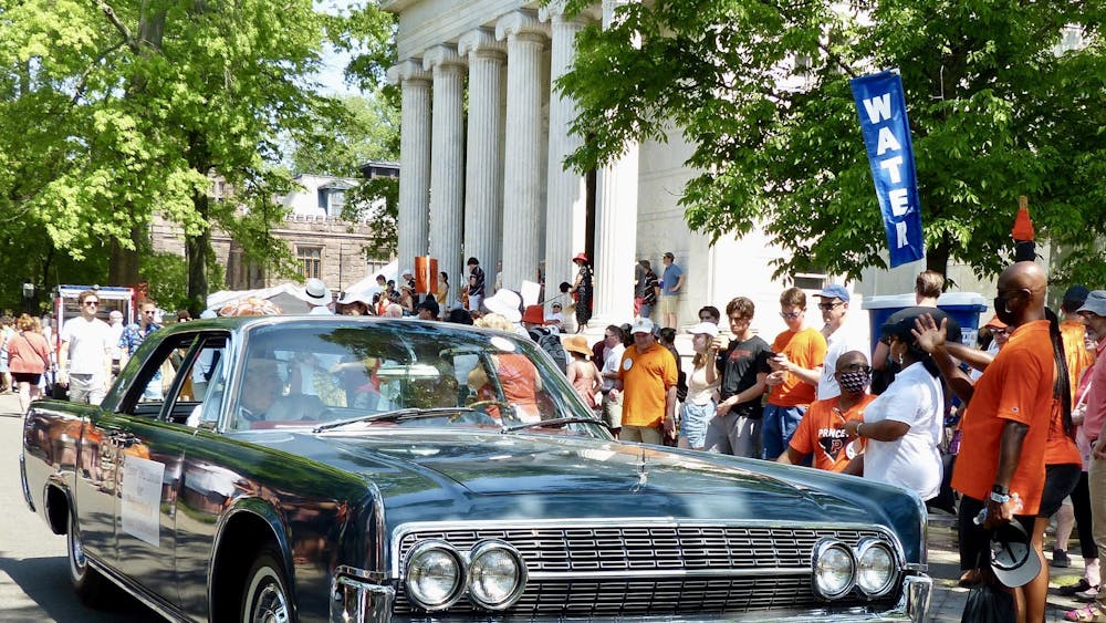 Green car in front of crowd of onlookers.